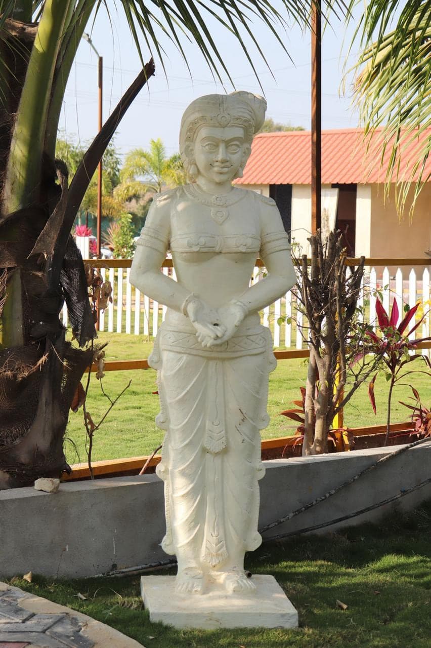 Carved stone statue on the lawn beside the picket fence at Mytri Farmhouse near Kondapochamma Sagar, Siddipet