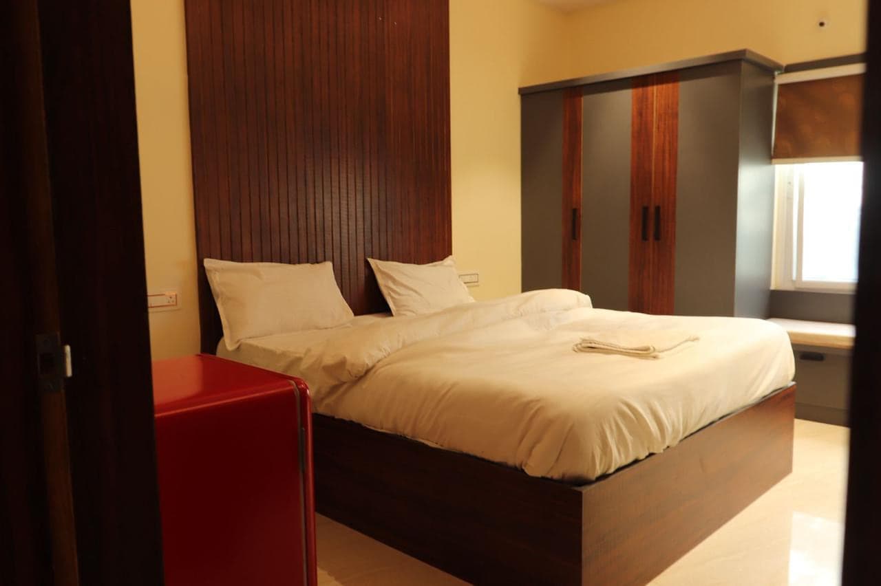 Double bed, wooden headboard and wardrobe in a guest room at Mytri Farmhouse near Kondapochamma Sagar, Siddipet