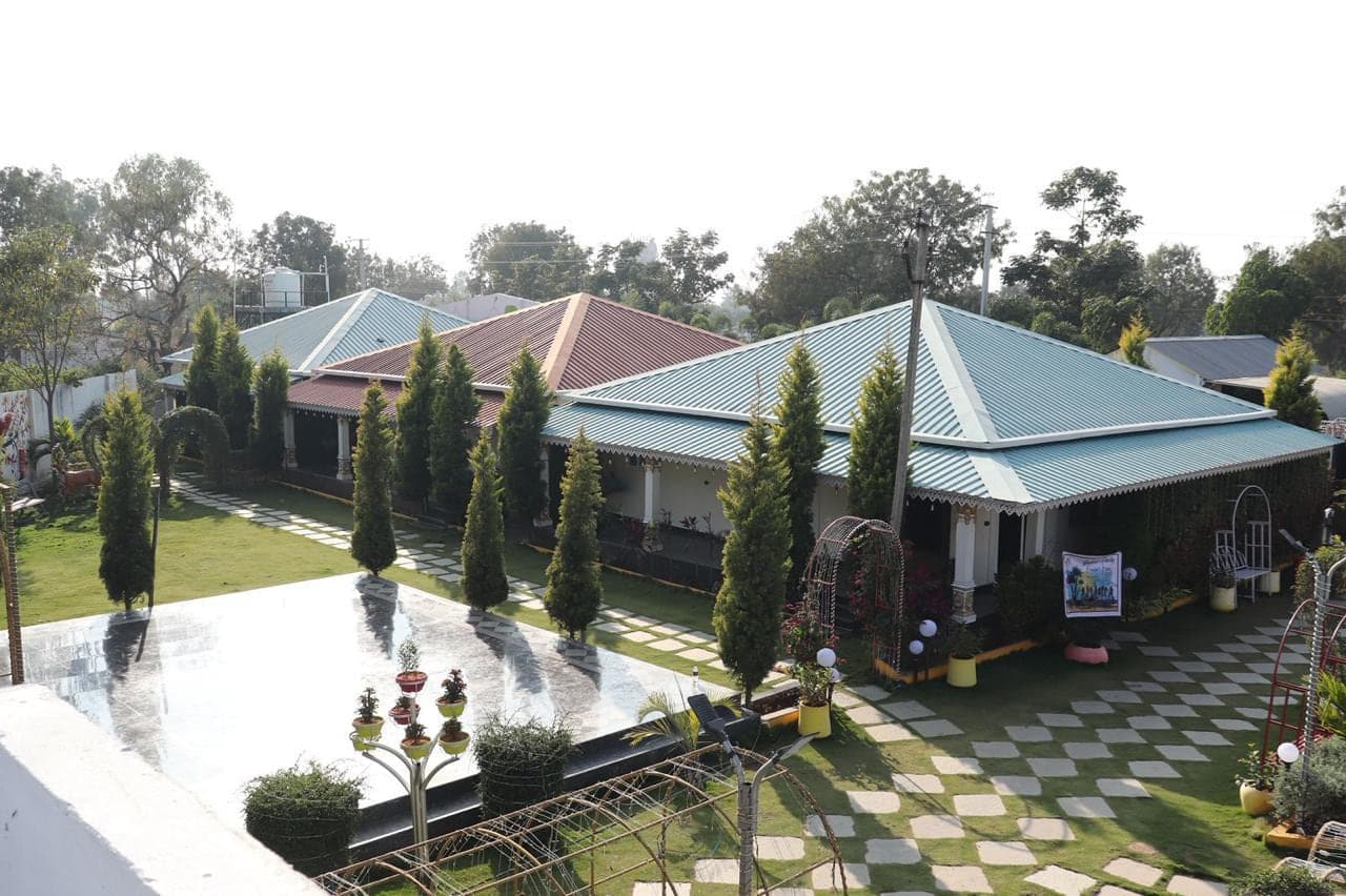 Guest room block with green tiled roofs, lawns and garden paths at Mytri Farmhouse near Kondapochamma Sagar, Siddipet