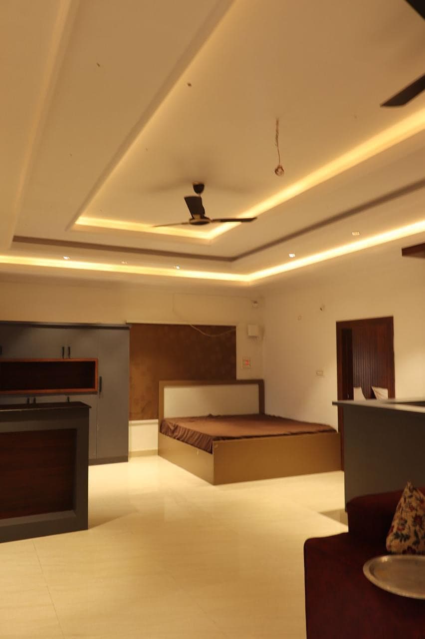 Bed, sofa and cove lighting inside one of the larger units at Mytri Farmhouse near Kondapochamma Sagar, Siddipet