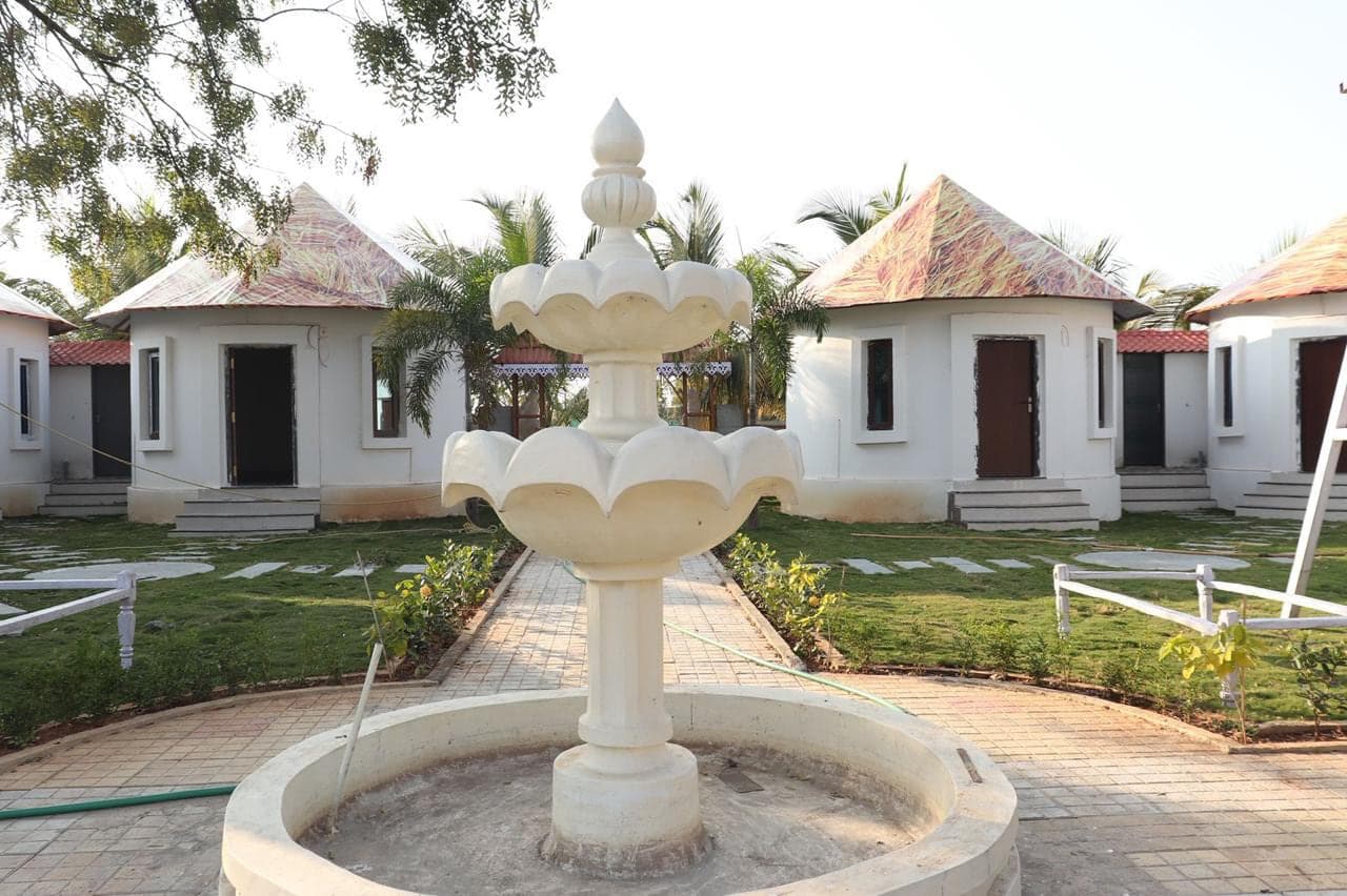 Tiered stone fountain on the path between guest cottages at Mytri Farmhouse near Kondapochamma Sagar, Siddipet