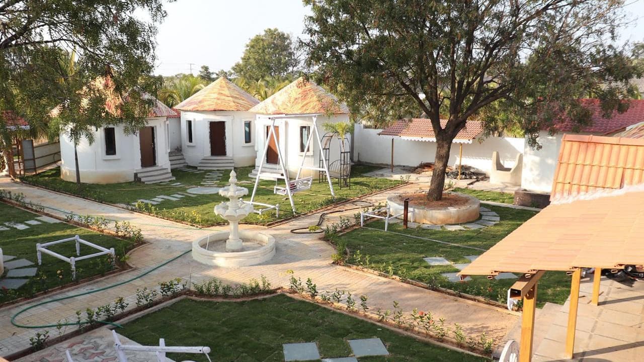 Central courtyard with a garden swing and round cottages at Mytri Farmhouse near Kondapochamma Sagar, Siddipet