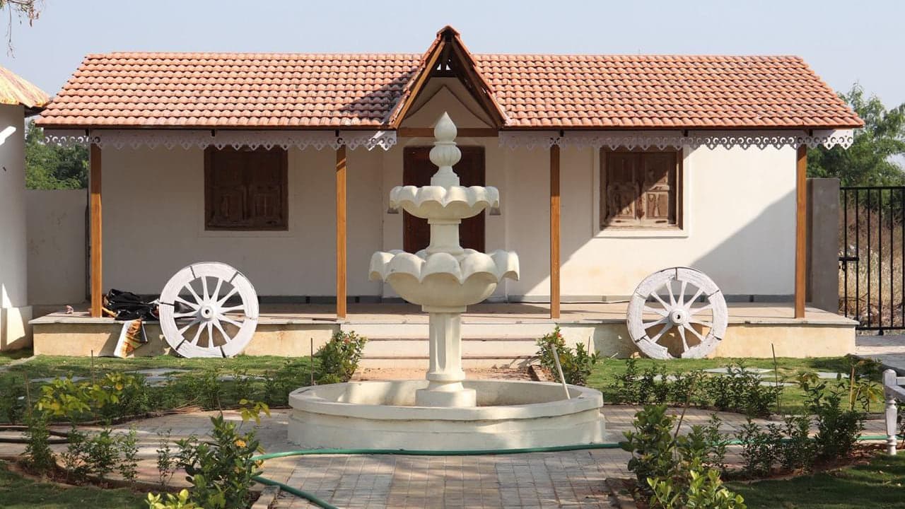 Traditional cottage with carved doors, a fountain and painted cart wheels at Mytri Farmhouse near Kondapochamma Sagar, Siddipet