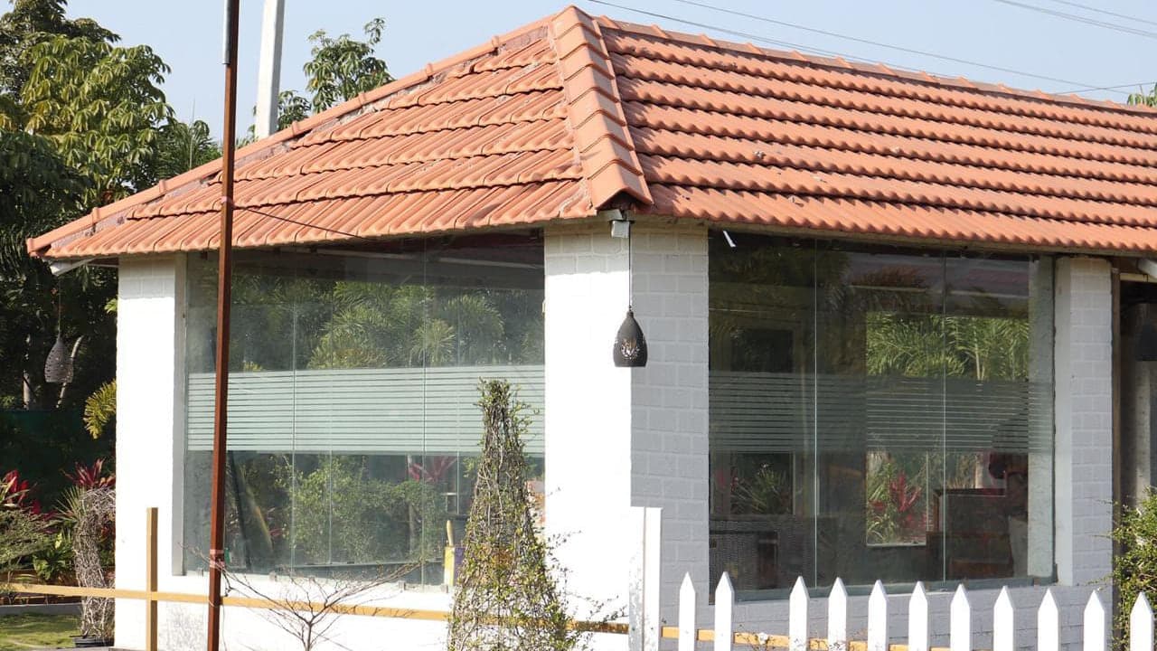 Glass-fronted pavilion beside the lawn at Mytri Farmhouse near Kondapochamma Sagar, Siddipet
