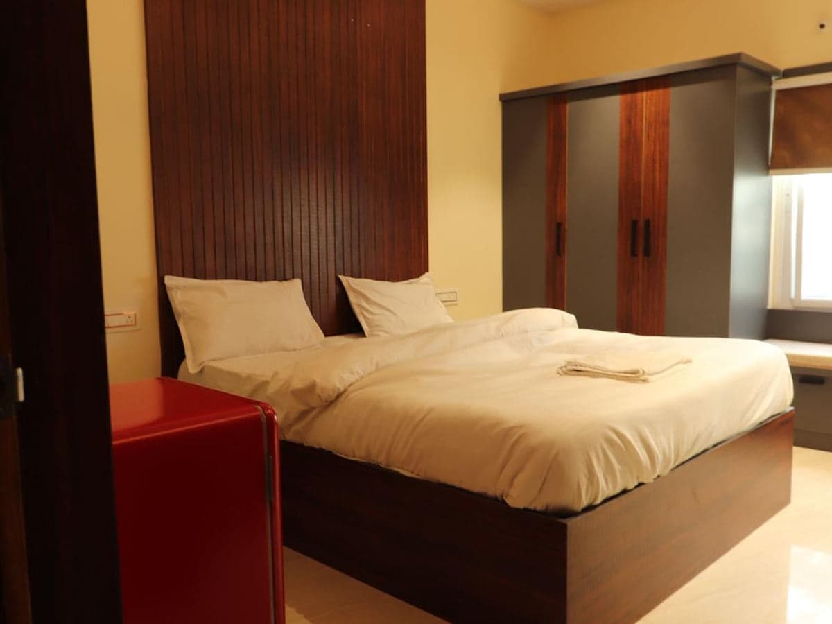 Double bed, wooden headboard and wardrobe in a guest room at Mytri Farmhouse near Kondapochamma Sagar, Siddipet