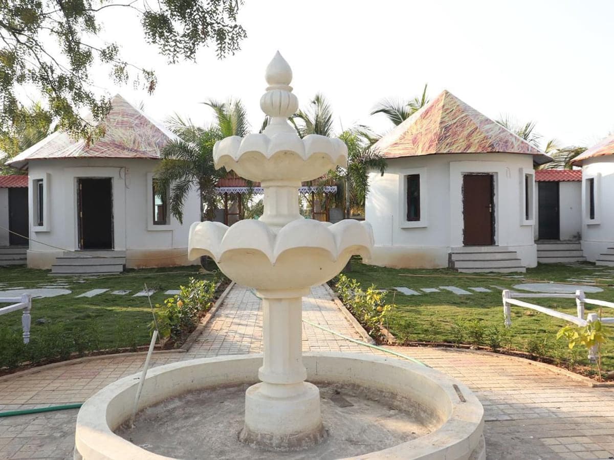 Row of guest cottages around the courtyard fountain at Mytri Farmhouse near Kondapochamma Sagar, Siddipet